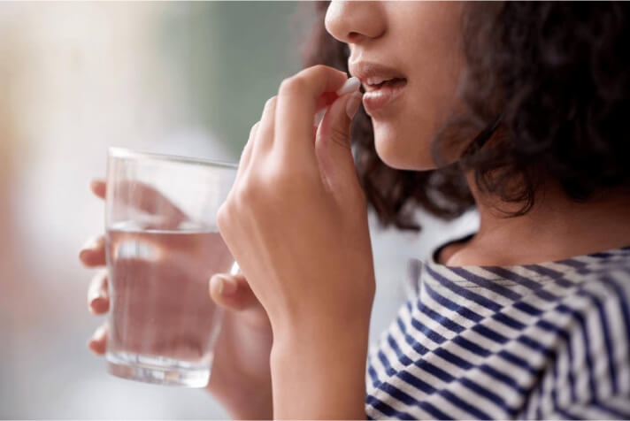 Una mujer tomando suplementos dietéticos.